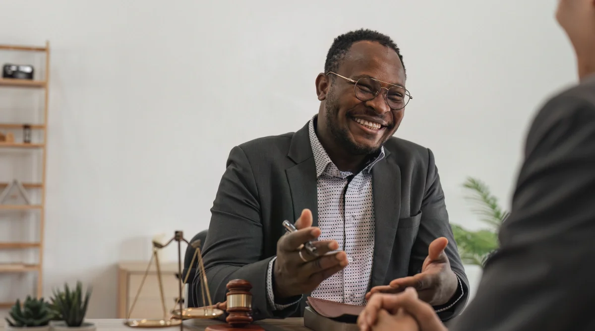 A man wearing a suit jacket and glasses smiling
