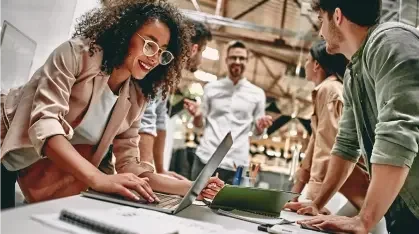 A group of coworkers discussing business plans around a computer laptop