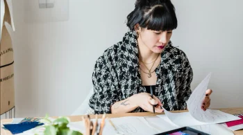 A woman sits at her desk and reviews her patent designs.
